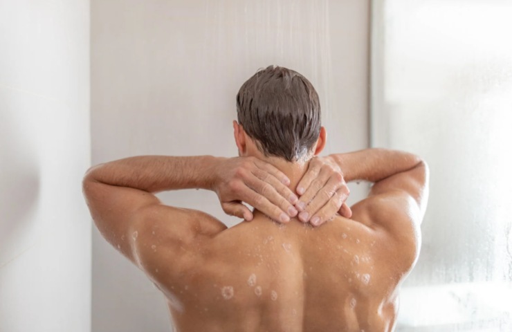 uomo voltato di spalle sotto alla doccia